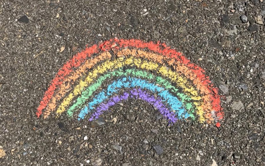 A beautiful chalk rainbow is drawn on the pavement of the driveway.