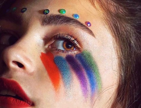 Girl with rainbow painted makeup around her eye.