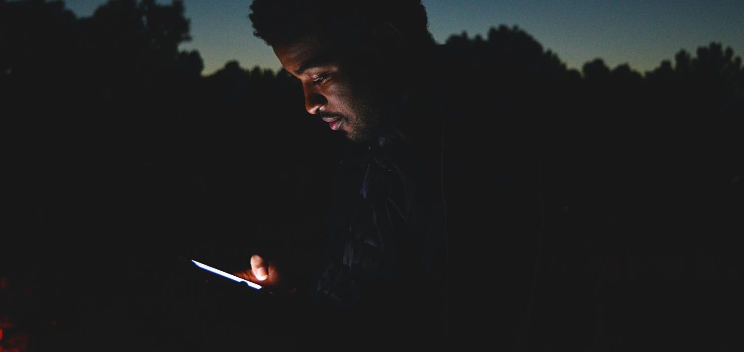 dark picture of a man on his phone